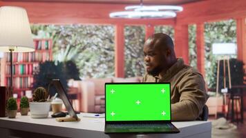Small business owner works on finances plans next to a green screen, using annual sales analytics to increase startup profit. Entrepreneur does budget balance analysis at home desk. Camera B. video