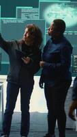 Vertical Cyber security experts women working on spyware and malware detection in a governmental agency. Examining server information on a big screen to combat cyberterrorism and cyberwarfare. Camera B. video