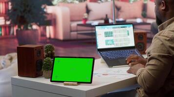 Financial expert reviews business statistics next to a chroma key screen, analyzing budget balance to ensure a correct economic situation report. Entrepreneur examines data analytics. Camera A. video