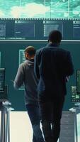 Vertical Governmental hackers analyzing cyber threats on big screens, managing important database hacking activity in high tech agency office. Work on cyber defense to protect national security. Camera B. video