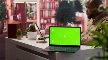 Small business owner works on finances plans next to a green screen, using annual sales analytics to increase startup profit. Entrepreneur does budget balance analysis at home desk. Camera A. video