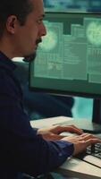 Vertical Governmental IT expert monitoring cyber threats on a computer and big screen, high tech agency office. Hackers examining cyber defense measures for prevention of dangerous digital threats. Camera A. video