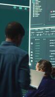 Vertical Governmental hackers analyzing cyber threats on big screens, managing important database hacking activity in high tech agency office. Work on cyber defense to protect national security. Camera A. video