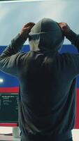 Vertical Russian hacker with a hood installing panic by misconception and manipulation, working in governmental cyber operations room. Impact of fake news and ideology propaganda in a hybrid war. Camera A. video