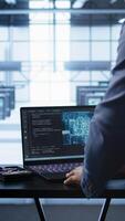 Vertical Engineer in server hub works with artificial intelligence computerized model simulating human brain. Man working on laptop with AI machine learning algorithms using pattern recognition, camera B video