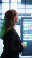 Vertical Engineer inspecting server room hardware, walking between supercomputers. IT professional supervising data center workplace, checking equipment, monitoring performance, camera B video