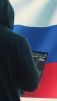 Vertical Propagandist person in a Russian cybersecurity center with the national flag works on installing fear and anxiety among the population by manipulation and brainwashing, cyber conflicts. Camera A. video