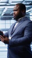 Vertical Developer in server hub checking recovery plan on tablet, monitoring hardware energy consumption. African american worker uses digital device in data center, ensuring rigs are functioning, camera B video