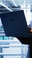 Vertikale Computer Wissenschaftler im hoch Technik Einrichtung mit Laptop zu Patch Netzwerk Probleme beeinflussen Server Schränke Performance und Konnektivität, führen zu Arm Klient Kommunikation, Kamera b video