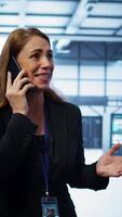 Vertical Technician in data center talking in phone call, doing yearly inspection. On field system administrator talking with manager in server hub during telephone call, monitoring servers, camera B video