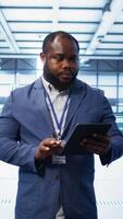 Vertical IT technician walking in data center, overseeing server operations using tablet. Expert ensuring optimal performance and data integrity in server hub using digital device, camera B video