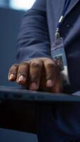 Vertical IT technician working on notebook in data center, overseeing server operations. Extreme close up shot of man ensuring optimal performance and data integrity in server hub, camera B video