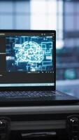 Vertical Laptop in data center facility with artificial intelligence computing simulating human brain, handheld camera shot. Close up of device displaying AI machine learning algorithms in server hub, camera A video