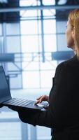 Vertical Technician doing yearly maintenance checkup using laptop to prolong data center hardware life span. IT specialist in server hub monitoring server infrastructure using notebook, camera A video