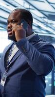 Vertical IT support worker in data center talking in phone call, doing yearly checkup. On field engineer chatting with manager in server hub during telephone call, monitoring servers infrastructure, camera B video