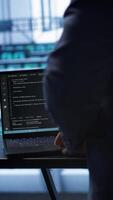 Vertical Engineer in server hub works with artificial intelligence computerized model simulating human brain. Man working on laptop with AI machine learning algorithms using pattern recognition, camera A video