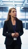 Vertical Admin walking in data center, monitoring systems to identify root cause of errors. IT specialist in server farm establishment doing diagnosis, looking for equipment bugs in need of repairing, camera B video