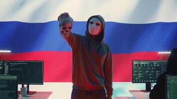 Russian cyber criminal with anonymous mask and hood holding a skull, making death threats and asking for ransom. Dangerous evil person symbolizing cyber threats and cyberterrorism. Camera B. video