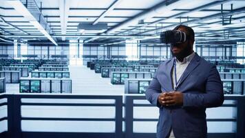 African american developer immersed in virtual reality at data center, doing units maintenance. Technician using VR headset to optimize servers performance, checking operations, camera B video