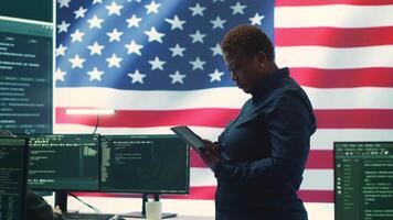 Cybersecurity specialists in a high tech office with the American flag, focusing on cyber intelligence and secure network operations. Works on information security and malware detection. Camera A. video