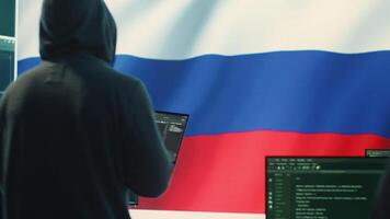 Propagandist person in a Russian cybersecurity center with the national flag works on installing fear and anxiety among the population by manipulation and brainwashing, cyber conflicts. Camera A. video