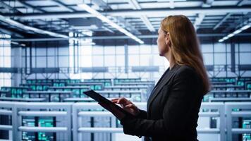 Computer scientist doing checkup, inputting data on tablet of needed fixes in server hub. Woman working in data center housing advanced data storage infrastructure supporting IT workloads, camera B video