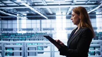 System administrator doing yearly maintenance using tablet to prolong data center equipment life span. IT expert in server hub workplace monitoring supercomputers using digital device, camera B video