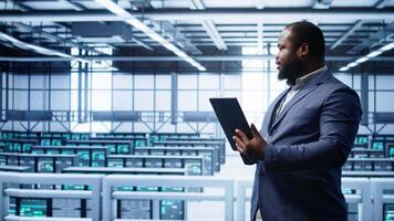 Software engineer in data center runs error checking utilities on tablet to fix problems. IT specialist looking for network issues affecting rigs performance using digital device, camera B video