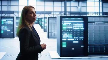 Engineer walking in data center workspace, monitoring systems to identify root cause of errors. Woman in server hub establishment doing diagnosis, looking for equipment bugs needing repairs, camera B video
