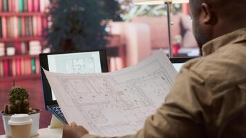 Business owner conducting strategic research on office spaces and building layouts, using blueprints and sketches to draft and organize a new creative workspace. Office hunt relocation. Camera A. video