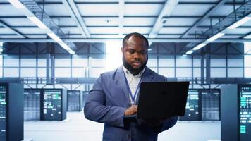 Computer scientist in data center using diagnostic tools and system monitoring software on laptop to identify cause of errors. IT specialist in server farm establishment repairing equipment, camera B video