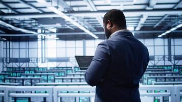 IT operator in server room workspace using tablet to patch network issues affecting transfer rates. Engineer in data center fixing errors affecting server rows rigs, camera B video