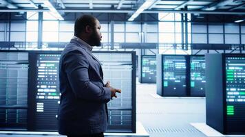Admin inspecting server farm equipment, walking between supercomputers. IT specialist doing evaluation of data center workspace, checking equipment, monitoring performance, camera B video