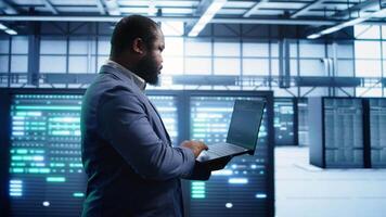 Technician in data center workspace running system diagnostic tests and error checking utilities to fix issues. Employee looks for network issues affecting rigs performance and connectivity, camera B video