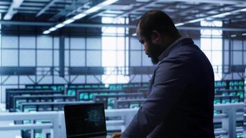 Software developer in data center using artificial intelligence computing simulating human brain. IT support staff member working on notebook with AI machine learning algorithms, camera A video
