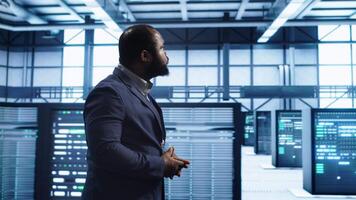 Admin inspecting server farm equipment, walking between supercomputers. IT specialist doing evaluation of data center workspace, checking equipment, monitoring performance, camera A video