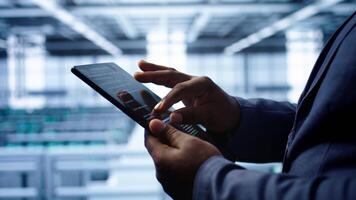 Software developer does yearly checkup using tablet to prolong data center electronics life span. Close up shot of worker in server room monitoring server infrastructure using digital device, camera B video