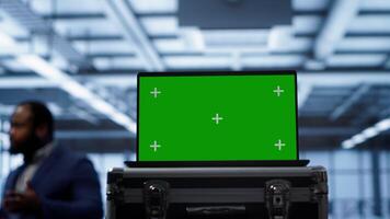 Green screen laptop used by engineers monitoring server room, doing checkup. Focus on chroma key notebook used by IT support employee working in data center facility, camera A close up video