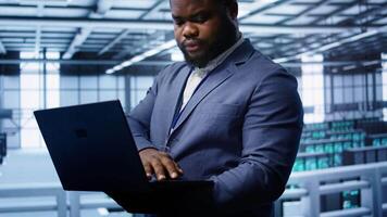 Software developer in data center runs diagnostic tests and error checking utilities on laptop to fix problems. IT expert looking for network issues affecting rigs performance using notebook, camera B video