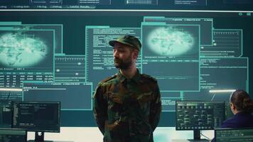 Military official private supervising governmental hacking activity in high tech office, looks at data on a big screen. Working on network safety, encryption and preventing cyberterrorism. Camera B. video