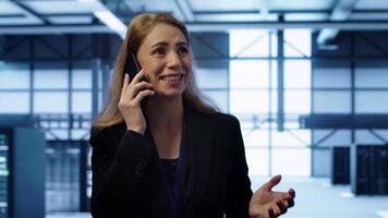 Technician in data center talking in phone call, doing yearly inspection. On field system administrator talking with manager in server hub during telephone call, monitoring servers, camera A video