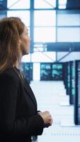 Vertical Engineer inspecting server room hardware, walking between supercomputers. IT professional supervising data center workplace, checking equipment, monitoring performance, camera A video