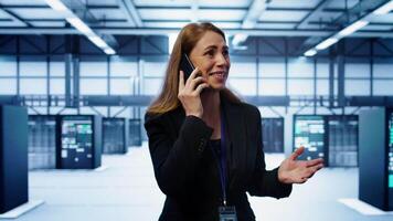 Technician in data center talking in phone call, doing yearly inspection. On field system administrator talking with manager in server hub during telephone call, monitoring servers, camera B video