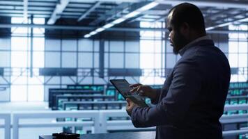 System administrator in server room establishment installing newly ordered storage unit. Software developer working in data center facility housing storage rackmounts, camera A video