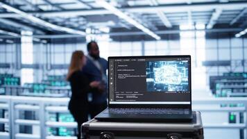 Laptop in data center facility with artificial intelligence computing simulating human brain, handheld camera shot. Close up of device displaying AI machine learning algorithms in server hub, camera B video
