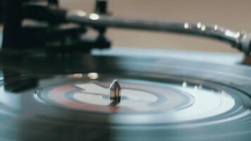 Close-up of a hand which changing song on a vinyl record by moving the turntable needle on a vintage record player. Concept of warm indoor atmosphere of enjoying music video