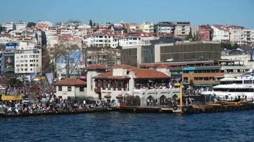 Istanbul, Turkey - February 24, 2024, View of The Besiktas Pier, enormous crowd of people and some university campus buildings at the coast of Besiktas. video