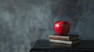 A red apple sitting on top of a stack of books on top of a black table next to a gray wall with smoke coming out of the back of it photo