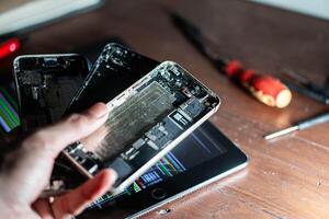 Disassembled smartphone parts and coding on tablet photo
