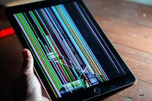 Tablet with broken screen displaying colorful lines photo